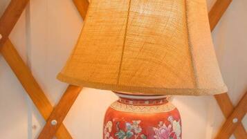A lamp with a woven shade on a table with a pink crocheted placemat.