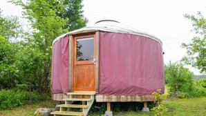 A yurt with a wooden door and a small set of steps leading up to it, surrounded by greenery. - Farm Stay Yurt - 7 min St Albans (Fairfield)
