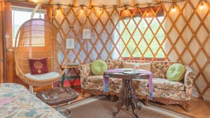 A cozy interior with a wicker chair, floral sofa, and a small table. - Farm Stay Yurt - 7 min St Albans (Fairfield)