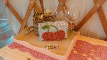 A wooden tray with a woven basket containing utensils, a decorative box, and a glass of water.