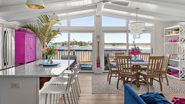 Una cocina luminosa con una isla grande, sillas de madera y una mesa de comedor.