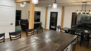 A modern kitchen with a wooden dining table, black chairs, and pendant lights.