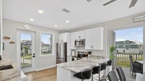 Una cocina moderna con armarios blancos, electrodomésticos de acero inoxidable y encimera de mármol.