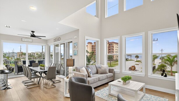 Un amplio salón con mesa de comedor, sofá y grandes ventanales con vistas a la playa y edificios.