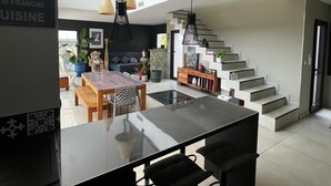 Eine moderne Küche mit einer zentralen Kochinsel, schwarzen Barhocker und Pendelleuchten.