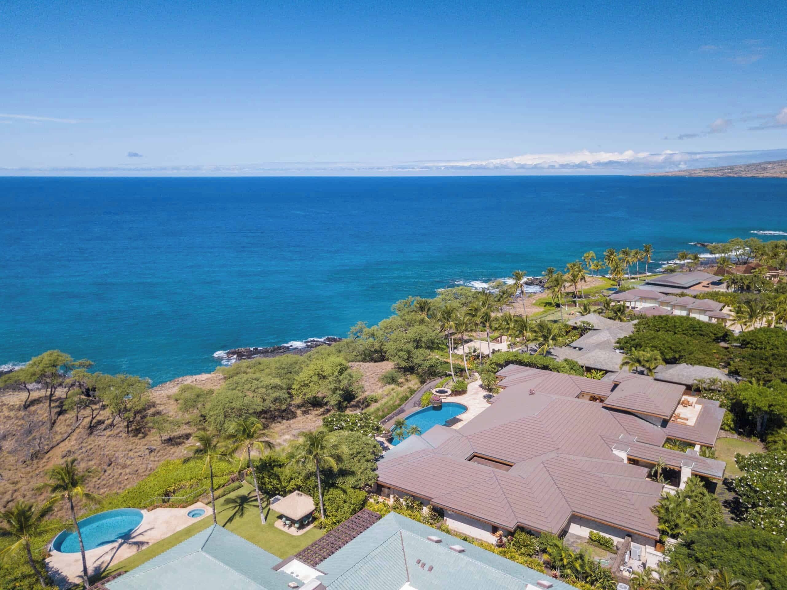 Una zona residenziale sul lungomare con case, una piscina e vista sull'oceano.