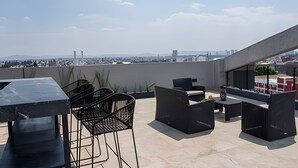 A rooftop terrace with outdoor seating, a table, and a view of a cityscape in the background. - Apartment with Beautiful Views | ACASO 502 (Heroica Puebla de Zaragoza)