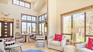 A spacious living room with large windows, a dining area, and a cozy seating arrangement.