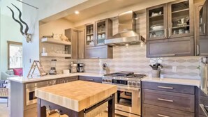 A modern kitchen with dark cabinetry, a central island, and a stainless steel range hood.