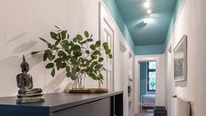 A hallway with a dark blue wall, a Buddha statue, and a potted plant on a dresser. - City apartment in the countryside, super central but completely quiet. (Kassel)