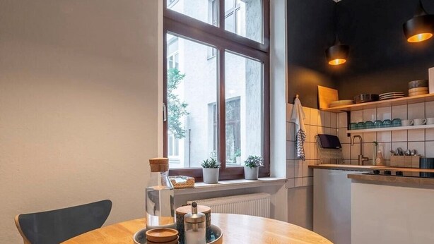 A modern kitchen with a round wooden table, built-in shelves, and pendant lighting. - City apartment in the countryside, super central but completely quiet. (Kassel)