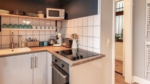 A compact kitchen with a microwave, toaster, and kettle on the countertop, a built-in oven, and a sink. - City apartment in the countryside, super central but completely quiet. (Kassel)