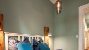 A bedroom with a white headboard, two beds with blue bedding, a hanging light fixture, and a wooden accent wall. - City apartment in the countryside, super central but completely quiet. (Kassel)
