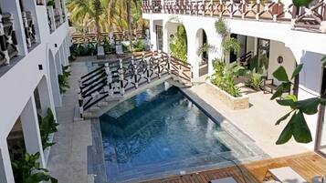Resort com piscina, deck de madeira e edifícios com telhado de palha.