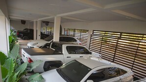 A parking garage with multiple cars parked in rows, large windows with blinds, and a staircase leading to another level. - Selanna 2 Luna Creciente (El Paredon)