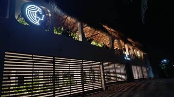 Un bâtiment à l’architecture moderne, doté d’un grand logo illuminé sur la façade et d’une toiture en chaume.