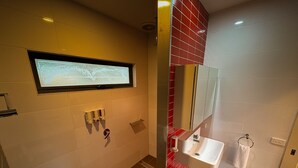 A modern bathroom with a large mirror, a sink, and a window. - DE 3 - Deluxe Open Plan Cabin (Cape Otway)