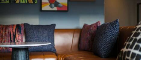 A brown leather sofa with patterned cushions and a small round table in front.
