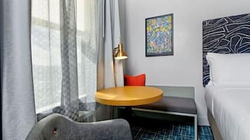 Quarto de hotel com cama, mesa redonda, sofá e uma cadeira.