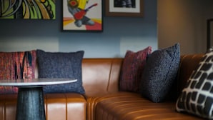 A brown leather sofa with patterned cushions and a small round table in front. - Relaxing Double Room with Rooftop Pool, Near Pier 39 & Coit Tower (San Francisco)