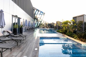 A modern outdoor pool area with lounge chairs and a glass-enclosed seating area.