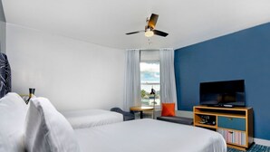 A hotel room with two beds, a TV, a ceiling fan, a window with curtains, and a small table with a chair. - 2 Comfortable Room with Rooftop Pool, Near Oracle Park & Yerba Buena (San Francisco)