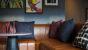 A brown leather sofa with patterned cushions and a small round table in front. - 2 Family-Friendly Units Cozy Room, Steps to Yerba Buena & Rooftop Pool in SF (San Francisco)