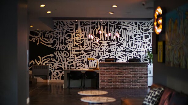 A modern lobby with a brick fireplace, round tables, and abstract wall art. - 2 Family-Friendly Units Cozy Room, Steps to Yerba Buena & Rooftop Pool in SF (San Francisco)