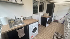 A compact laundry room with a washing machine, a sink, and a drying rack.
