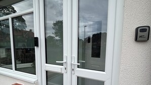 A set of white-framed glass doors with a keypad lock, a small brick ledge, and a textured wall.