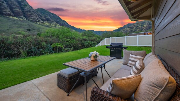 Eine Terrasse im Freien mit Tisch und Sitzgelegenheiten, mit Blick auf eine üppige grüne Landschaft und Berge.