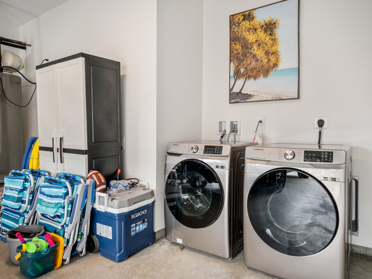 A laundry room with two front-loading washing machines, a drying machine, and a large cabinet.