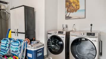 A laundry room with two front-loading washing machines, a drying machine, and a large cabinet.