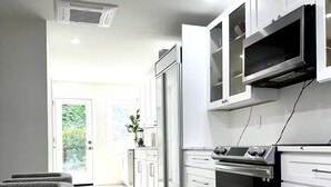 Une cuisine moderne avec des meubles blancs, un four encastré et une grande fenêtre.