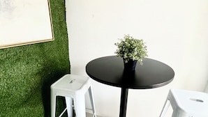 A small round table with a black base, a potted plant, and two white plastic stools. - Charming studio in Homestead with private backyard (Homestead)