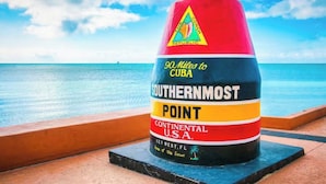A buoy with "90 Miles to Cuba" and "Southernmost Point" text, located near a beach with the ocean in the background. - Charming studio in Homestead with private backyard (Homestead)