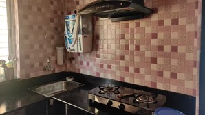 Une cuisine équipée d’une cuisinière à gaz, d’un évier, d’un distributeur d’eau et d’un crédence décorée.