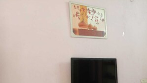 Un televisor de pantalla plana montado en la pared con un cuadro enmarcado encima.
