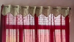 Una ventana con cortina roja y un adornado dobladillo.