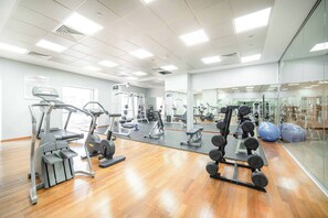 A gym with various exercise equipment, a mirrored wall, and a wooden floor. - Marina Tower 2602 (Dubai)