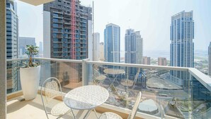 A balcony with a glass railing, a potted plant, and two patterned chairs.