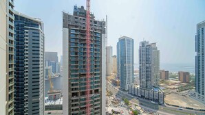 A high-rise building with a construction crane, surrounded by other tall buildings and a busy street.