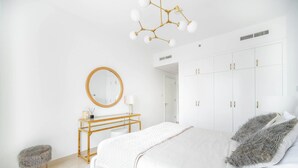 A modern bedroom with a large bed, a wooden bedside table, a round mirror, and a wardrobe.