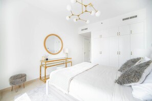A modern bedroom with a large bed, a wooden bedside table, a round mirror, and a wardrobe.