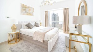 A modern bedroom with a large bed, a glass table, a mirror, and a view of tall buildings. - Marina Tower 2602 (Dubai)