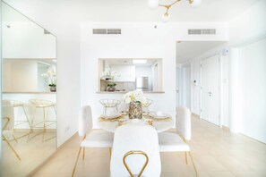 A modern dining area with a round table, white chairs, and a central vase of flowers. - Marina Tower 2602 (Dubai)