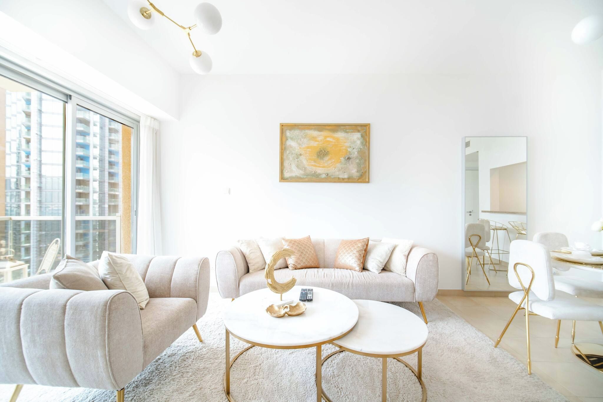 A modern living room with a sofa set, two round tables, and a large window offering a city view.