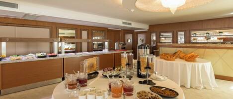 Un'area buffet con diversi cibi e bevande, un grande lampadario e un interno moderno e pulito.