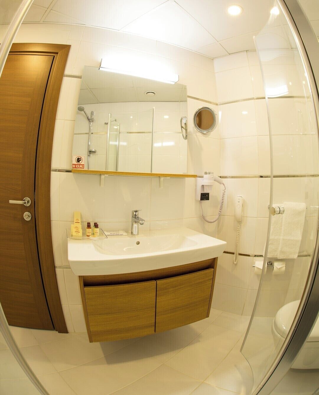 Un baño moderno con tocador de madera, lavamanos, espejo y cabina de ducha de vidrio.