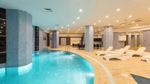 An indoor swimming pool with lounge chairs and a reception area.